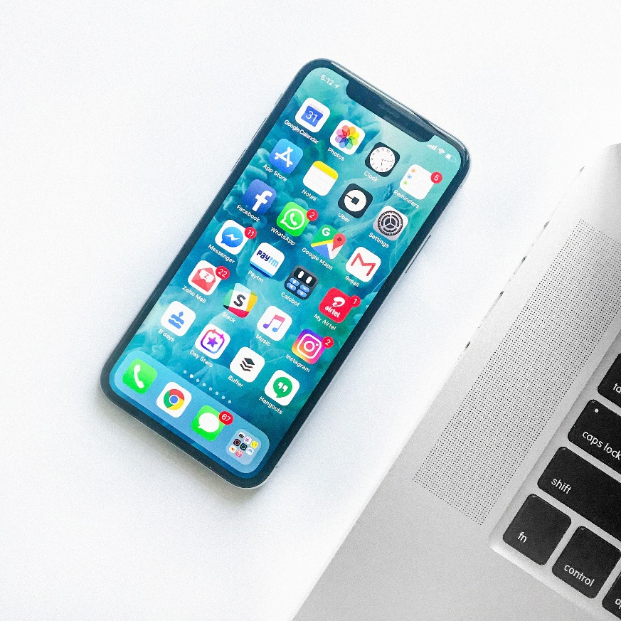 An iPhone and laptop lying on a white surface.